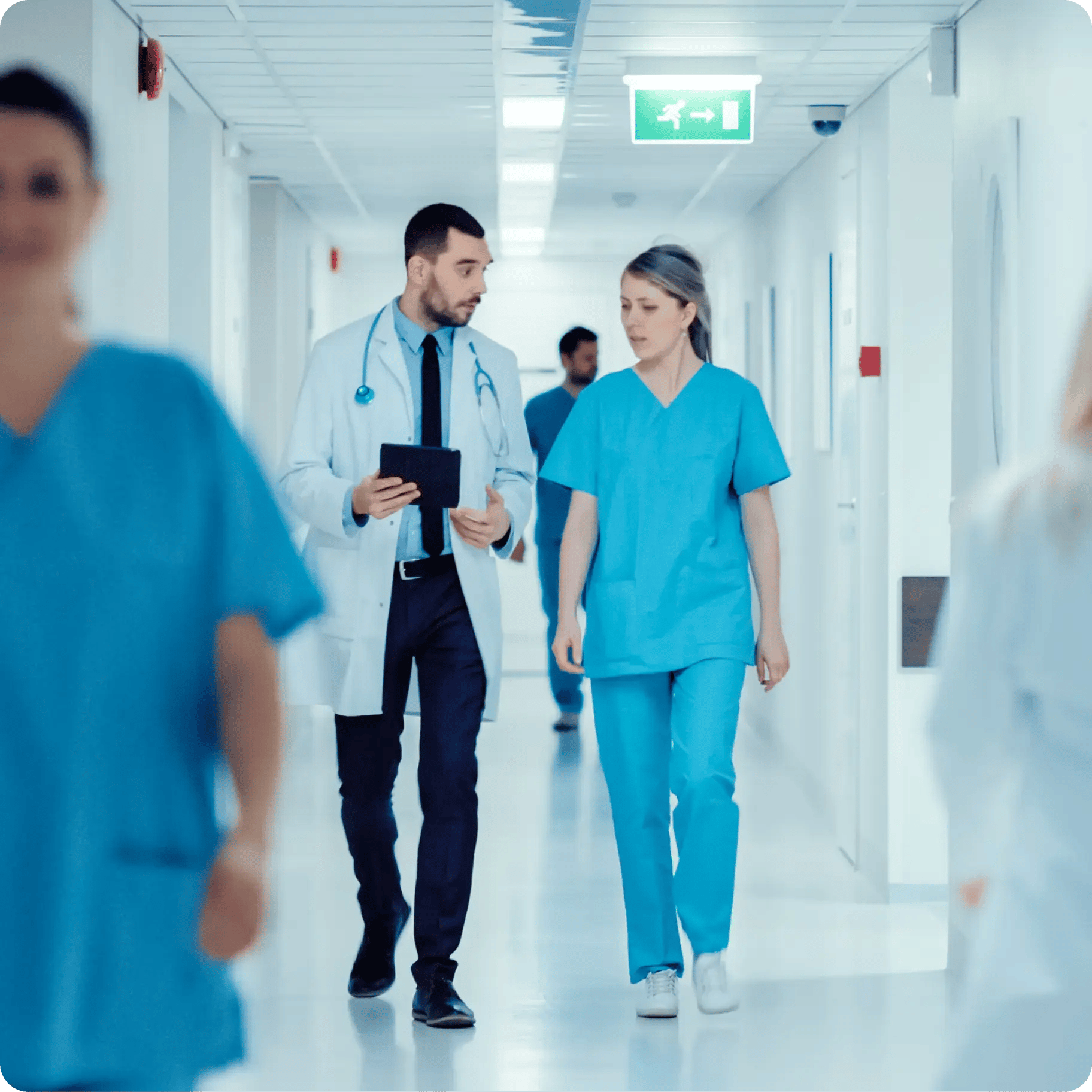 Surgeon and Female Doctor Walk Through Hospital Hallway
