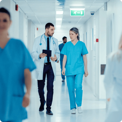 Surgeon and Female Doctor Walk Through Hospital Hallway