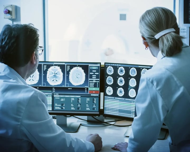 backshot of two doctors loking at brain scans on screens