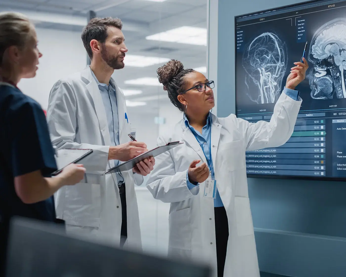 female doctor pointing at scans with two colleagues watching